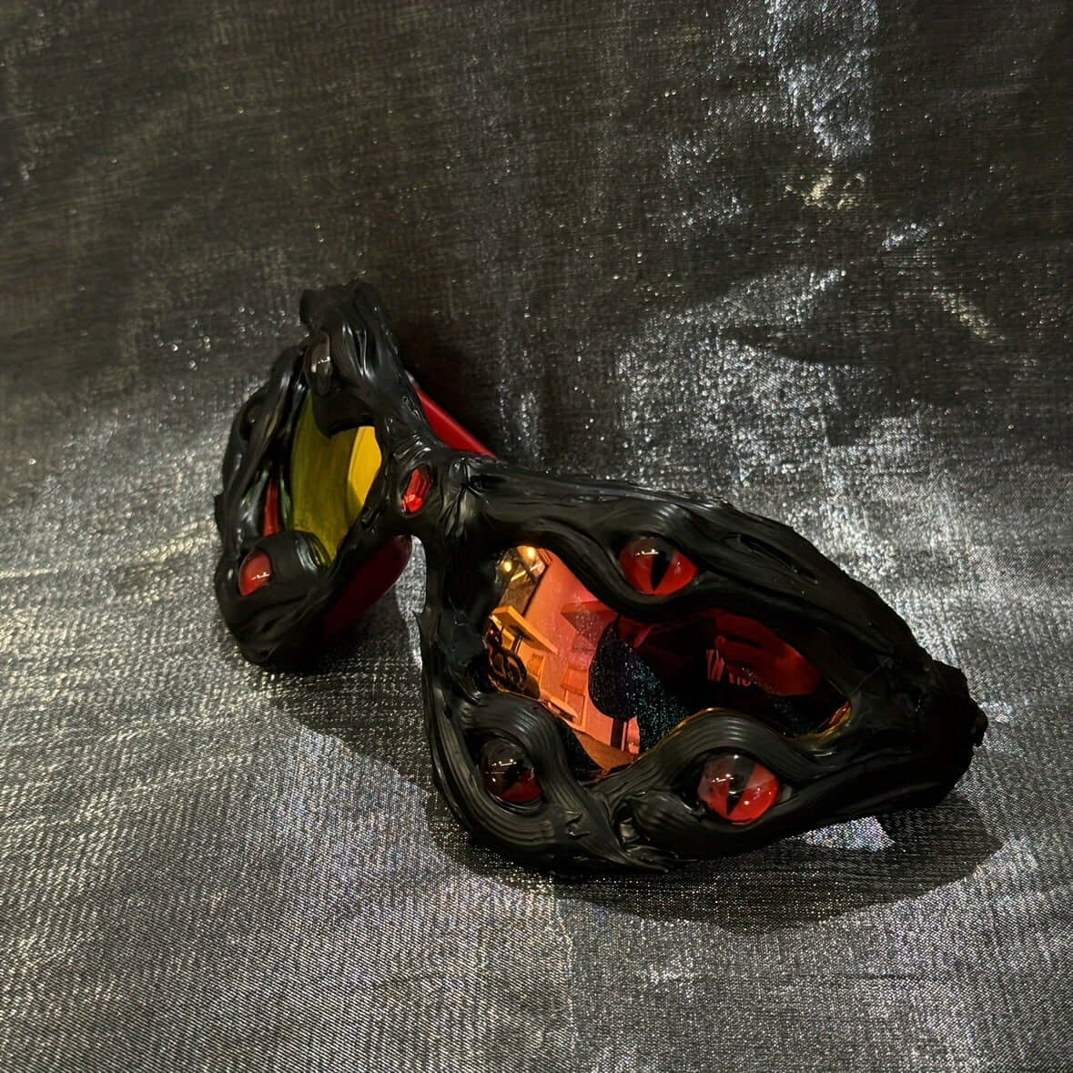 Handcrafted drip eyeglasses with unique design on textured background, unisex street style festival accessory in black and red.