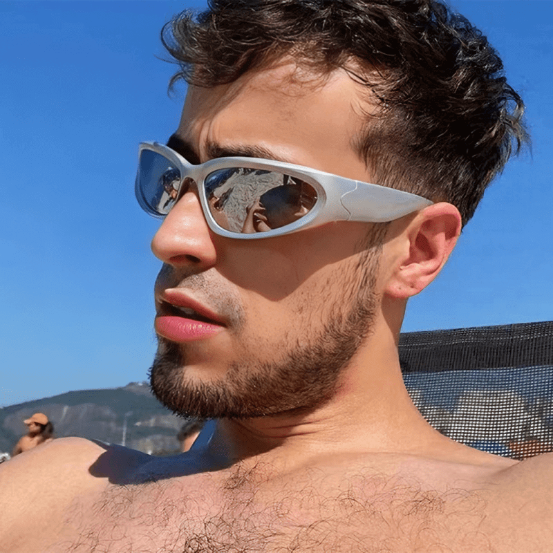 Person wearing vintage Y2K futuristic fashion sunglasses at the beach.