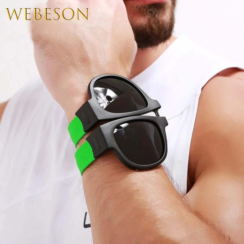 Foldable slap-on polarized sunglasses with green straps worn on man's wrist, ideal for sporty outdoor activities and travel.