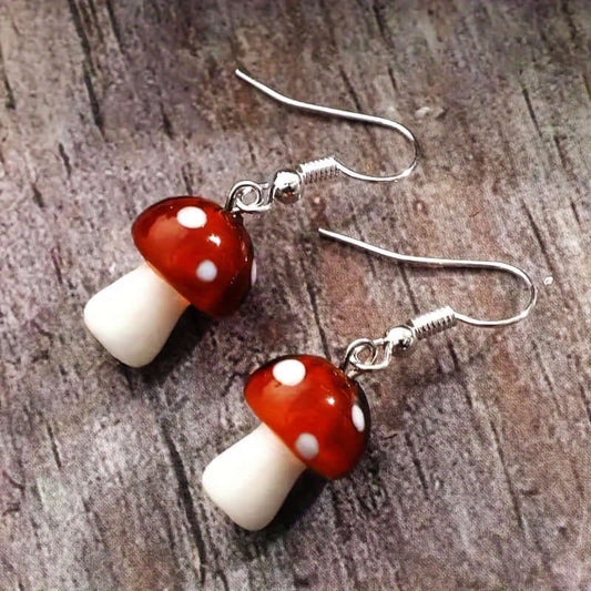 Vintage mushroom-shaped hook earrings with red and white caps, Y2K style jewelry on wooden background.