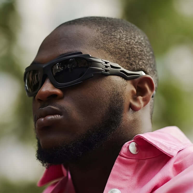 Man wearing Y2K steampunk fashion glasses with bold temples and black lenses in a stylish outdoor setting.