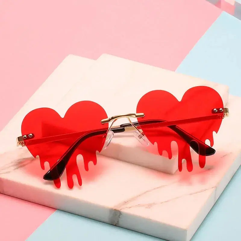 Heart rimless tear-shaped red sunglasses, unique steampunk style with UV400 protection, displayed on a marble background.