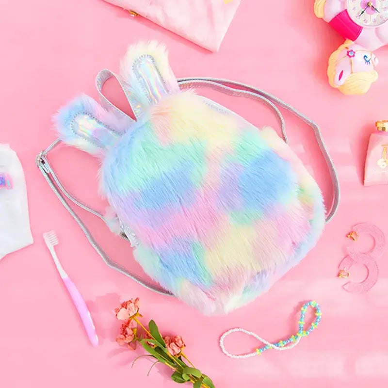 Kawaii unicorn rainbow mini backpack with plush ears and holographic accents on a pink background, ideal for festivals and parties.