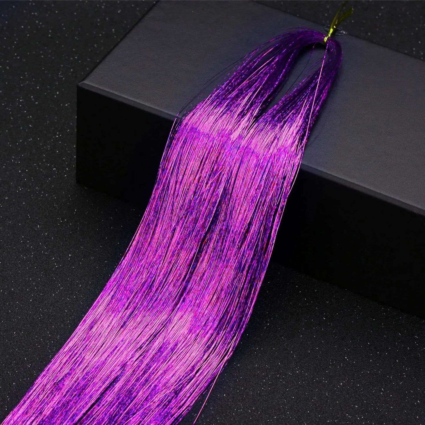 Vibrant purple glitter hair tinsel for parties and festivals, shown on a black box background.