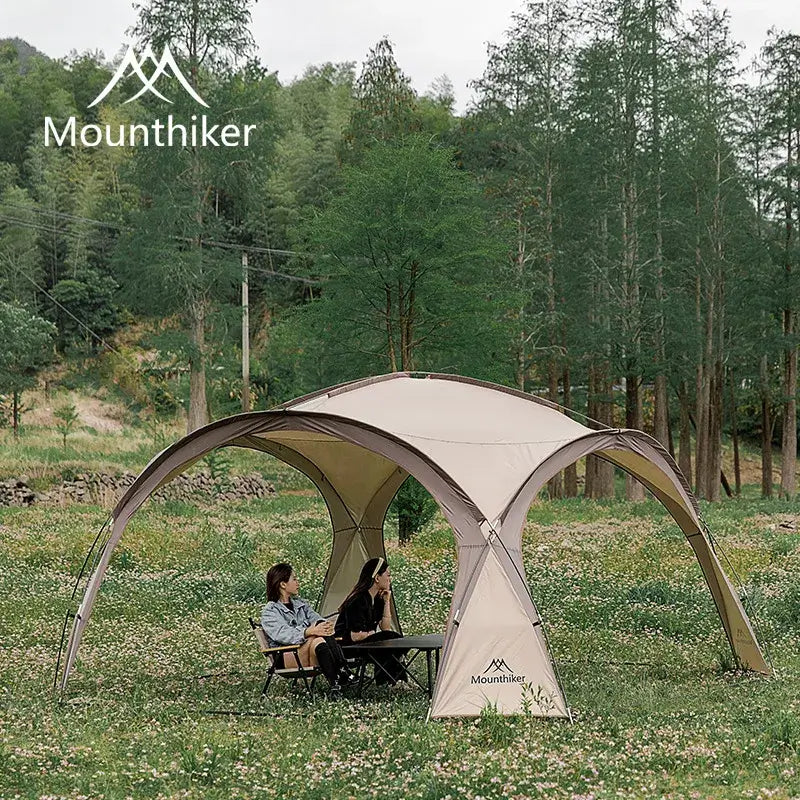 Spacious dome tent providing shade in a forest setting with two people sitting underneath, ideal for outdoor adventures.