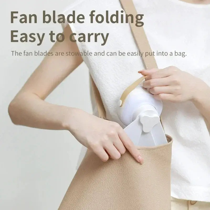 Woman placing foldable portable mini ceiling fan into a beige handbag for easy carrying.