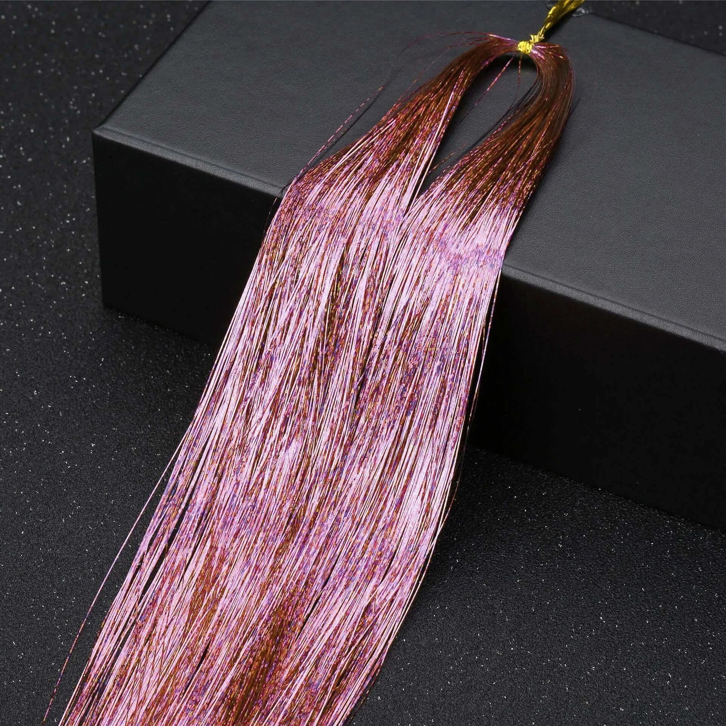 Pink glitter hair tinsel on black surface, part of a rainbow hair tinsel kit for party hairstyles and festival accessories.