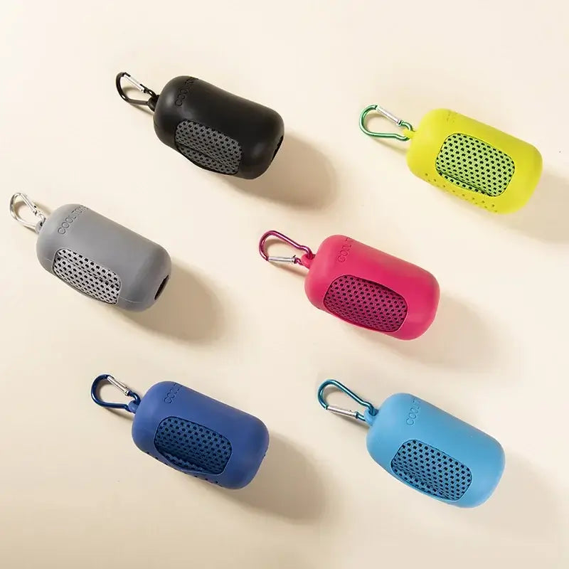 Six colorful portable Bluetooth speakers with carabiner clips on a beige background.