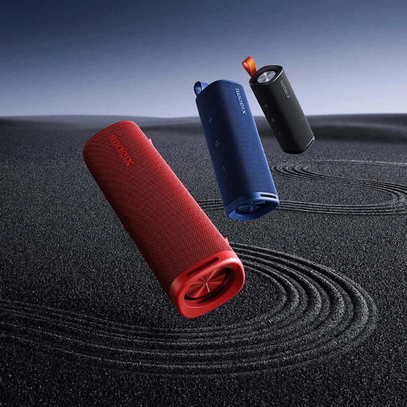 Three Xiaomi Sound Outdoor 30W Bluetooth speakers floating on a textured surface, showcasing vibrant red, blue, and black colors.