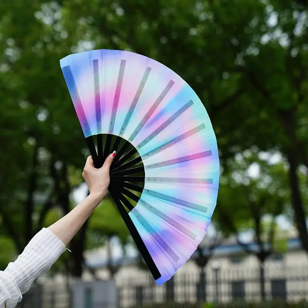 Gradient colorful reflective foldable rave fan held in hand outdoors, perfect accessory for festivals and party dances.