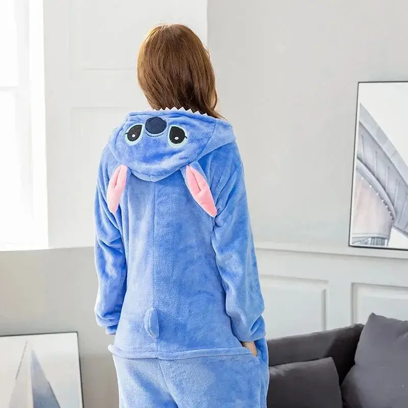 Adult wearing blue Stitch cartoon onesie costume with hood, showcasing cozy flannel fabric in a home setting.