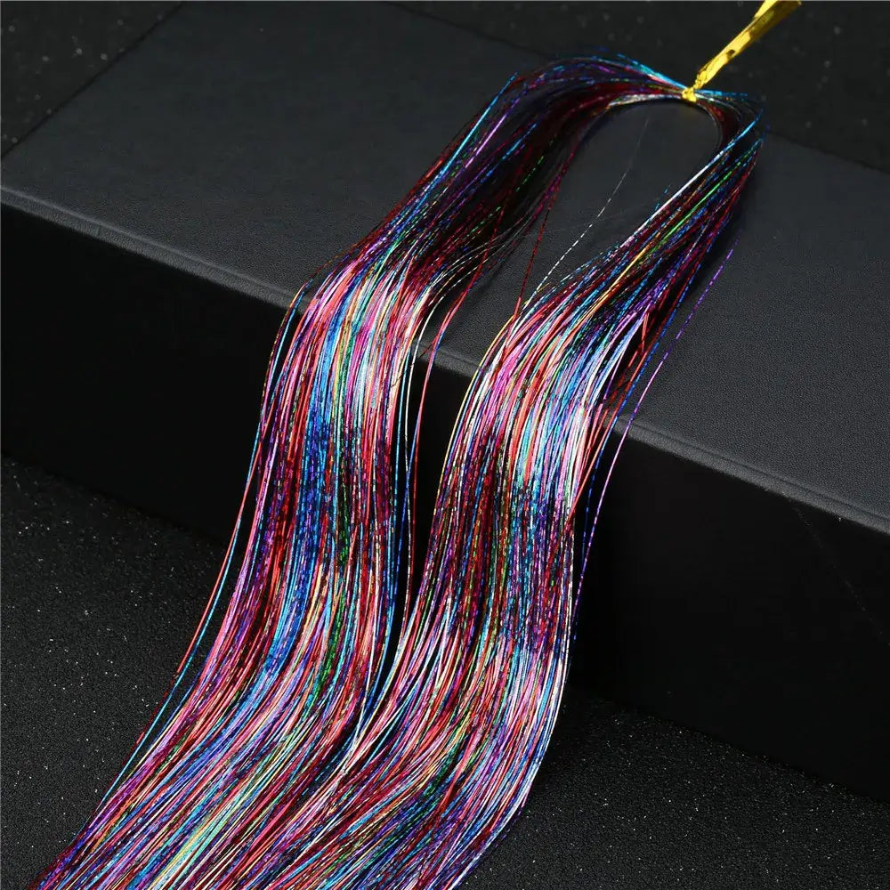 Vibrant rainbow glitter hair tinsel in 16 colors for striking party hairstyles, shown on a sleek black surface.