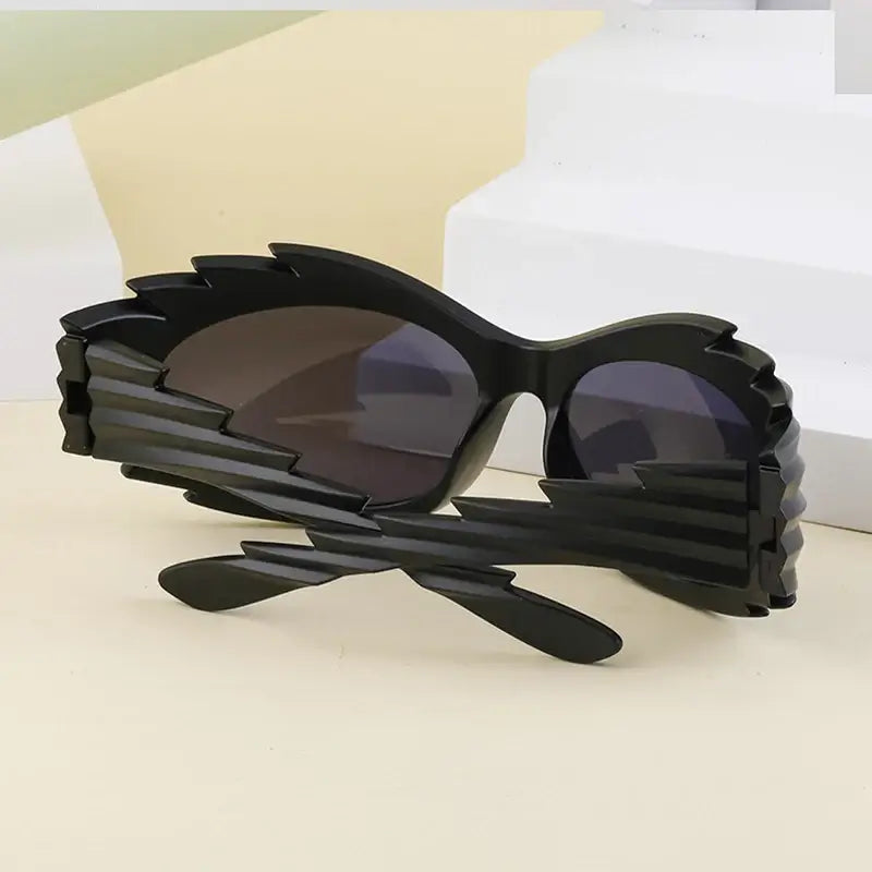 Black futuristic Y2K punk rave sunglasses with bold design and rimless lenses for men and women on display.