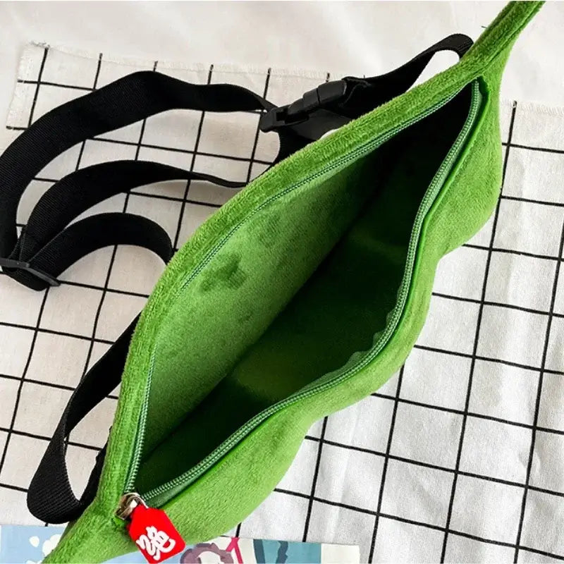 Green edamame pea shoulder bag with adjustable black straps, open to display interior on grid-patterned background.