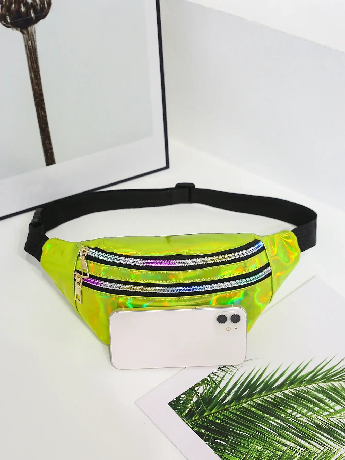 Holographic laser waist bag in vibrant yellow with adjustable black strap, designed for festival and travel use, shown with a smartphone.