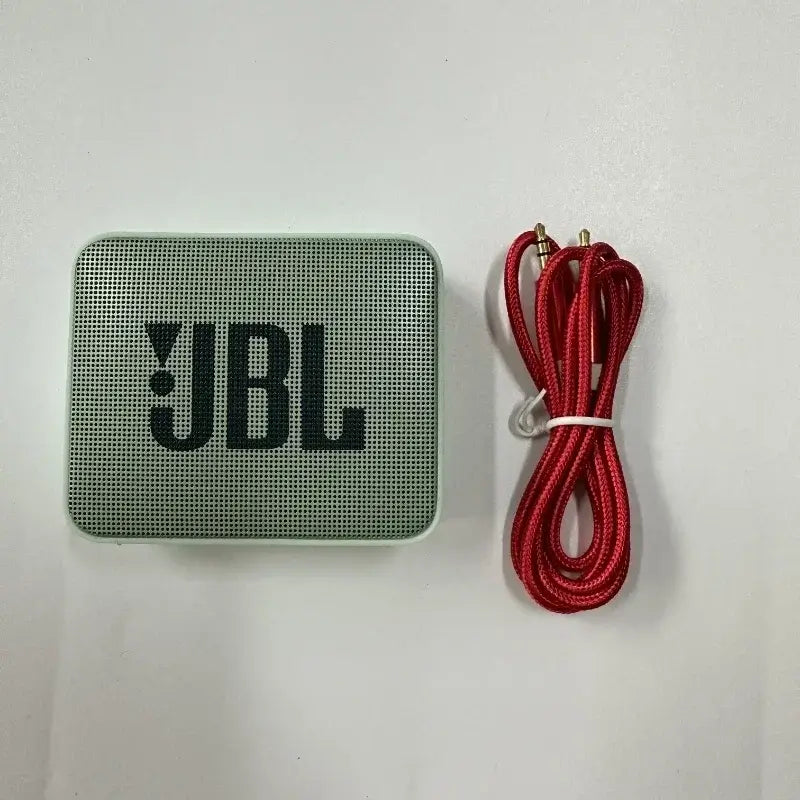 JBL GO 2 Bluetooth Speaker with red charging cable, compact and portable audio device for up to 5 hours playtime.