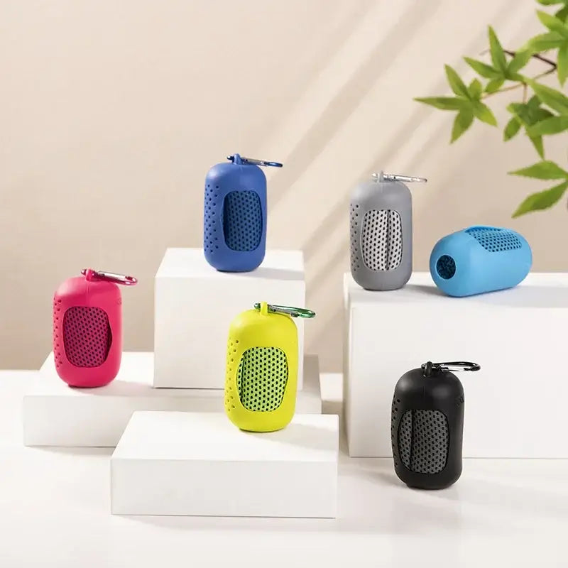 Colorful portable Bluetooth speakers displayed on white platforms with plants in the background.