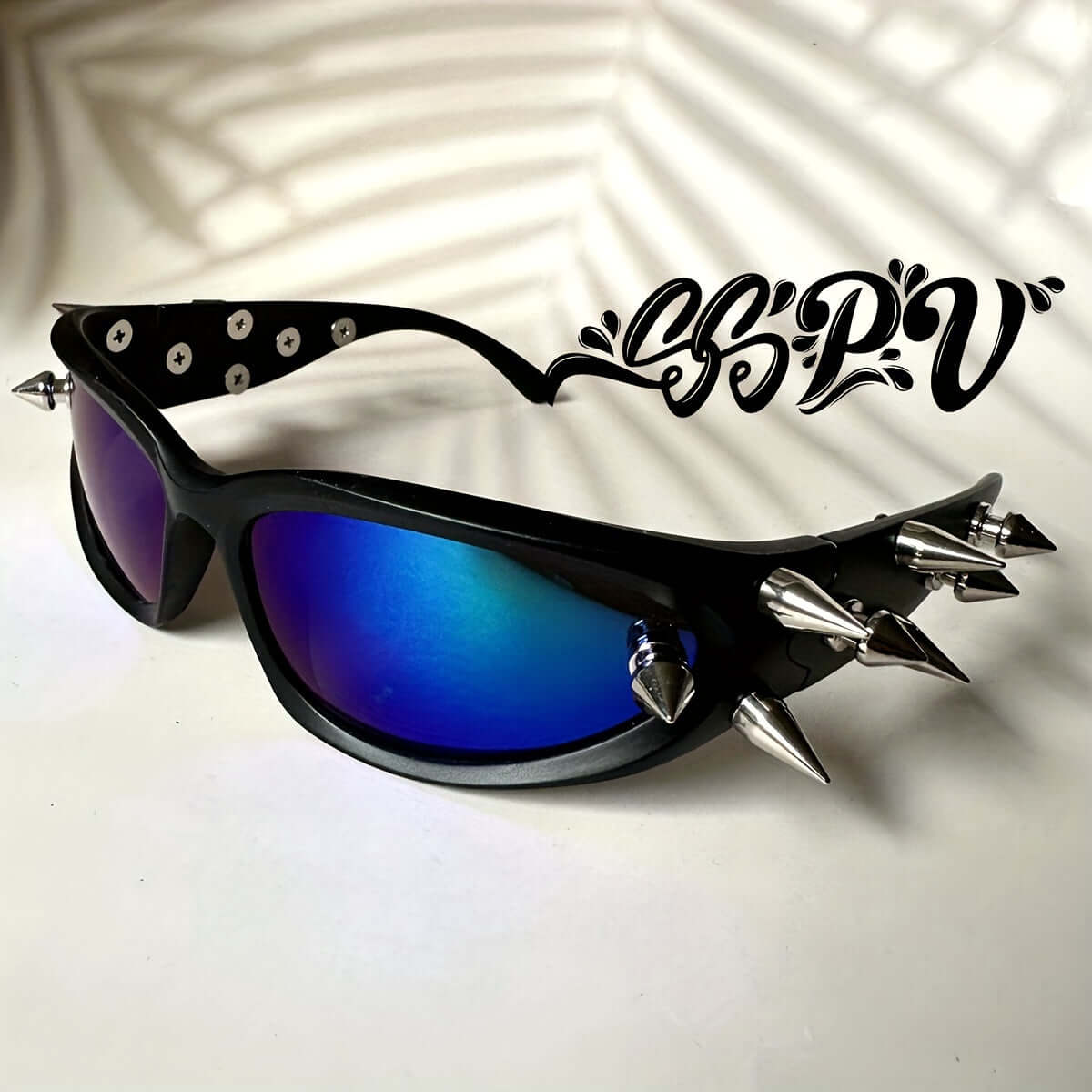 Cyberpunk cat-eye glasses with blue lenses, metal rivet accents, and spike details on a durable black frame. Ideal for rave fashion.