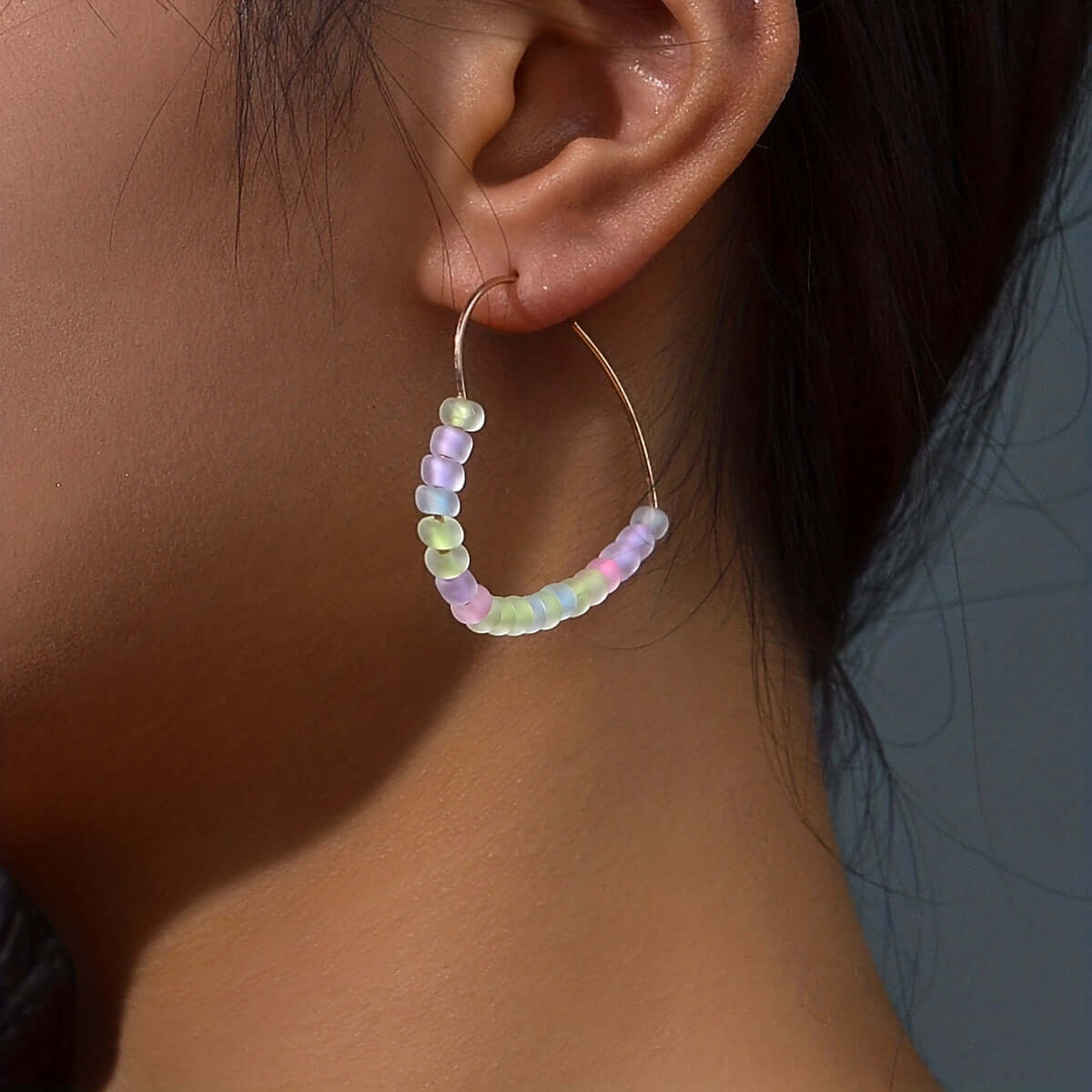 Close-up of glow-in-the-dark acrylic hoop earring with colorful beads, perfect for festivals and parties.